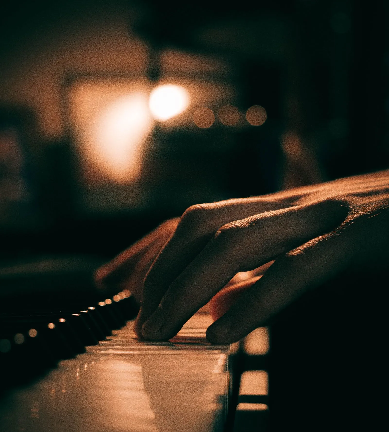 Hands playing piano in a dank ambience